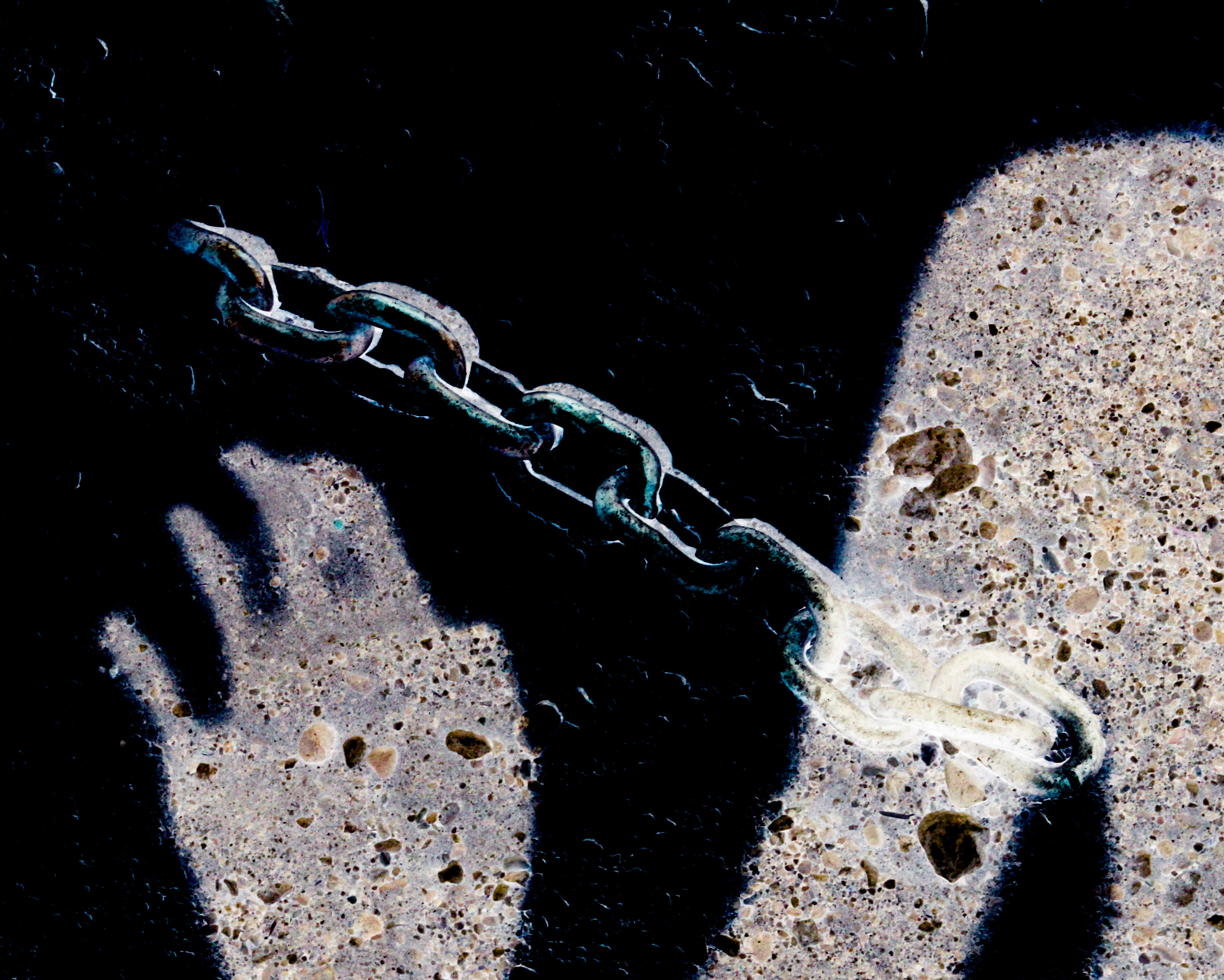 An inverted photograph of a shadow of a hand and a chain on the ground
